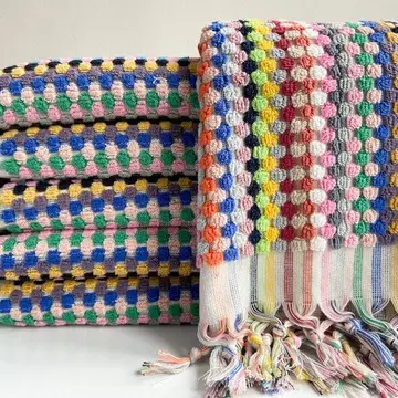A stack of multicolored hand towels with a geometric pattern.